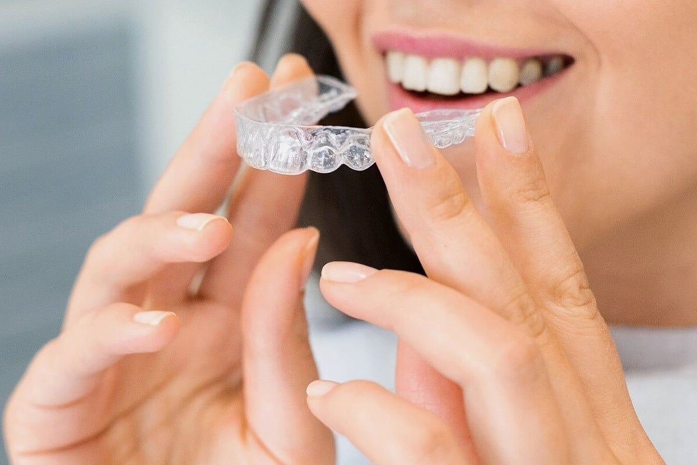 Alinhador transparente nas mãos de uma mulher, próximo ao sorriso