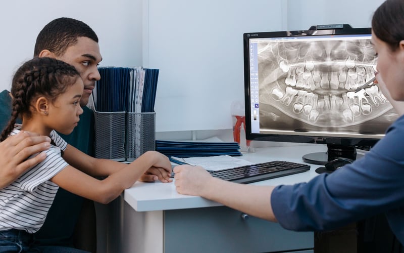Criança acompanhada pelo pai em uma consulta odontológica