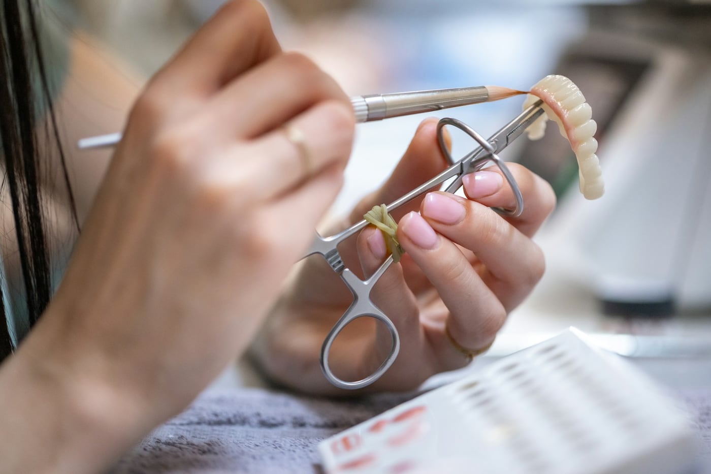 Prótese dentária sendo ajustada com instrumentos em laboratório