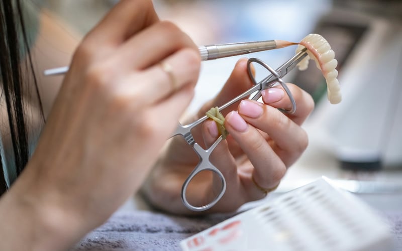 Prótese dentária sendo ajustada com instrumentos em laboratório