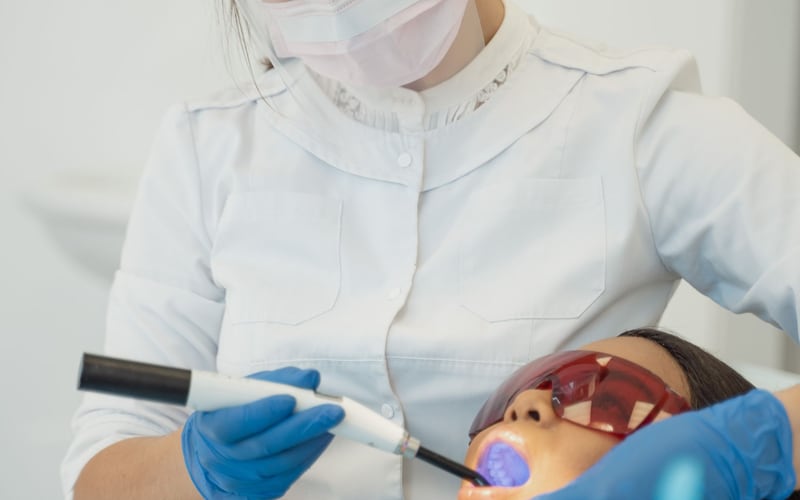 Dentista utilizando fotopolimerizador durante atendimento
